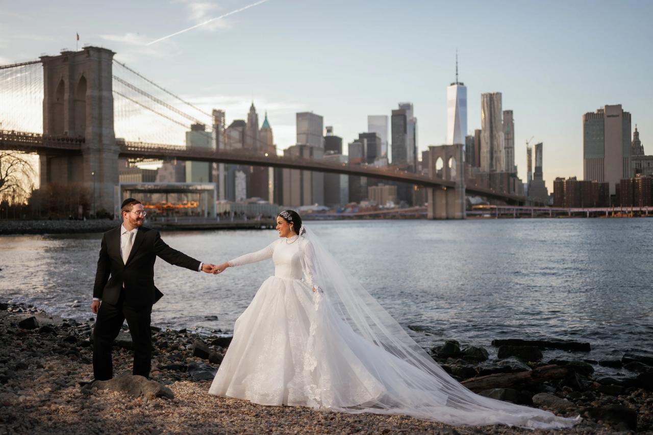 Groom holding the bride’s hand beside the Brooklyn Bridge