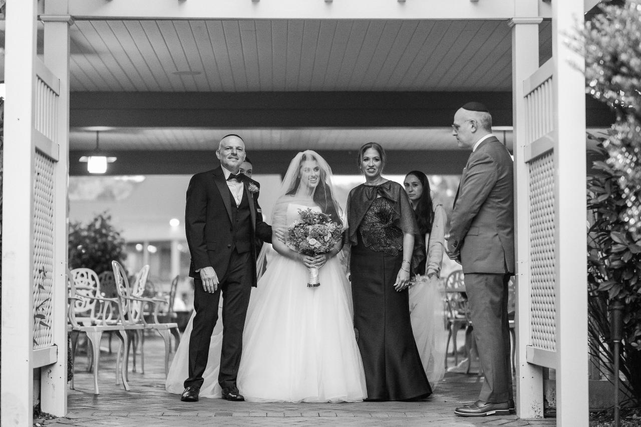 Wedding couple with family beneath the chuppah. Crest Hollow wedding in Woodbury, Long Island.