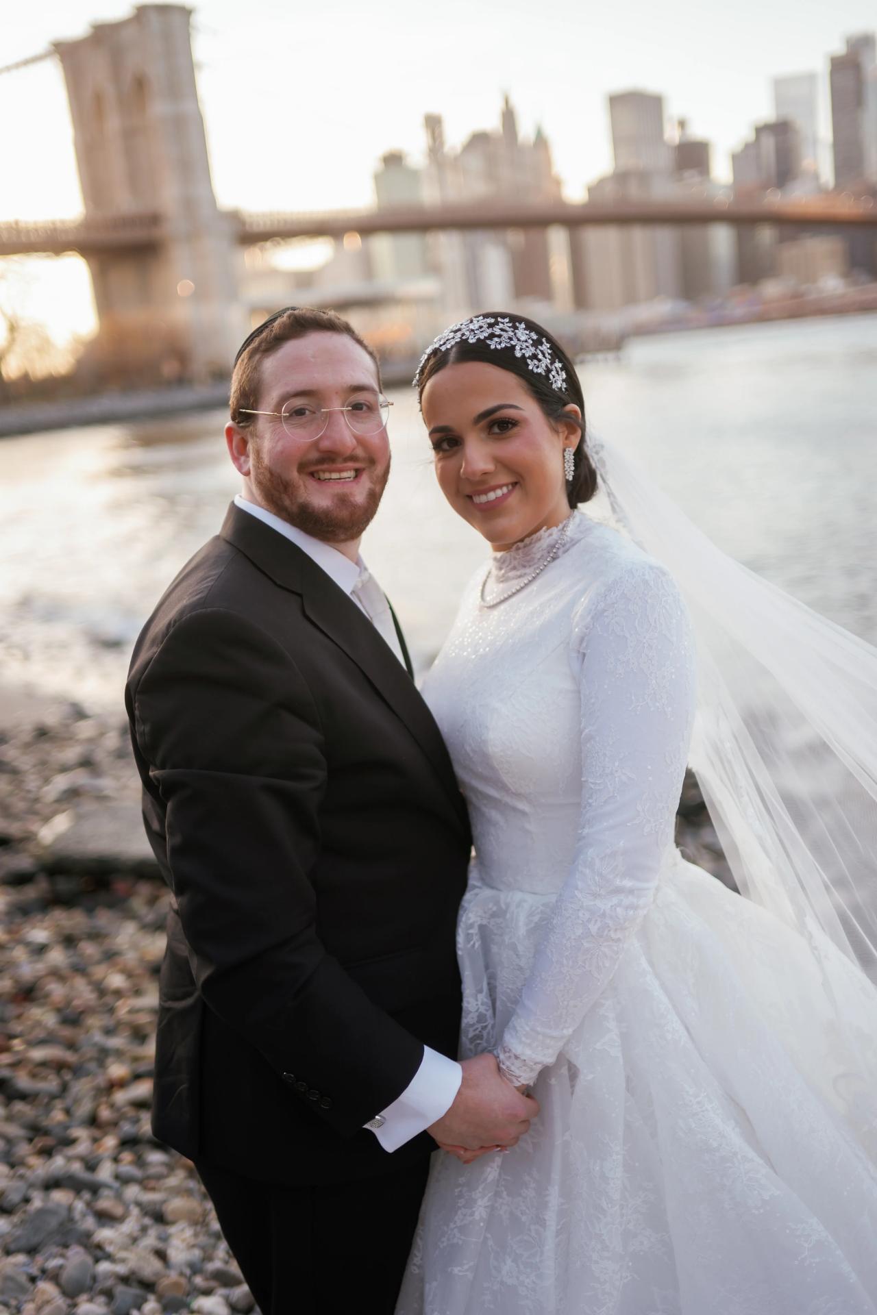 Bride and groom smiling together with the bridge behind them. Wedding portraits in Brooklyn, NYC.