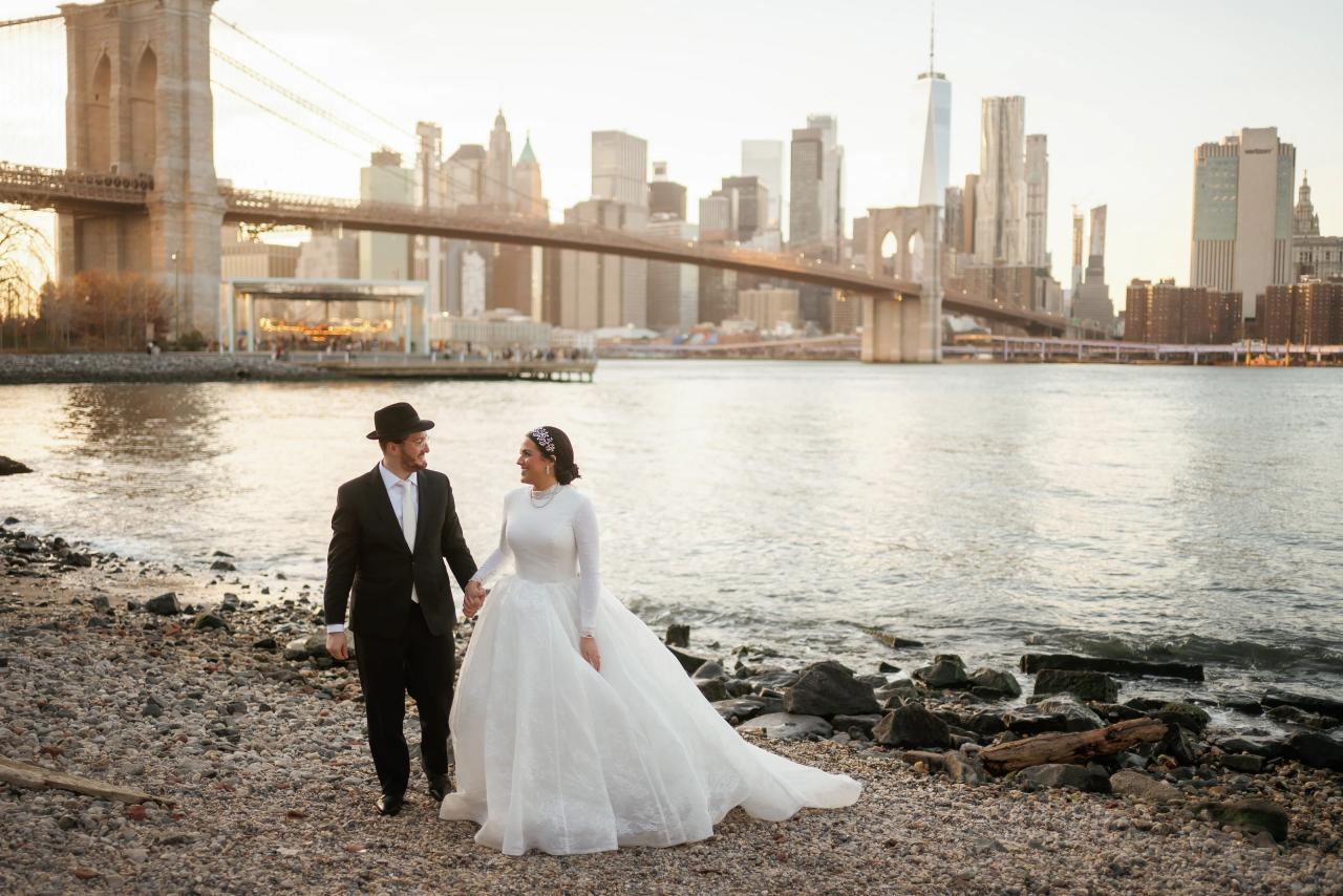 Wedding couple walking together along the rocky waterfront. Wedding portraits in Brooklyn, NYC.