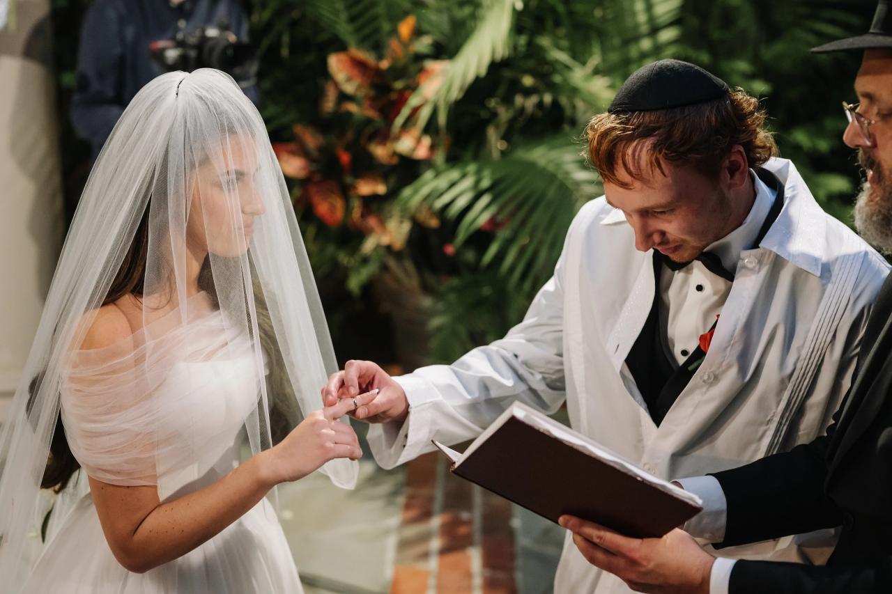 Wedding ring exchange beneath a floral chuppah. Crest Hollow wedding in Woodbury, Long Island.