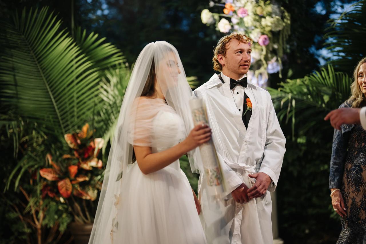 Wedding couple beneath the chuppah at dusk. Crest Hollow wedding in Woodbury, Long Island.