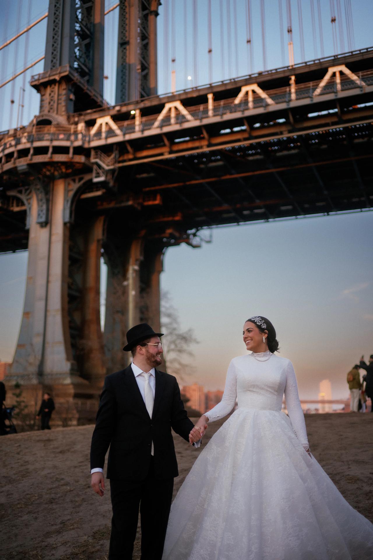 Groom leading the bride beneath the Manhattan Bridge. Wedding portraits in Brooklyn, NYC.