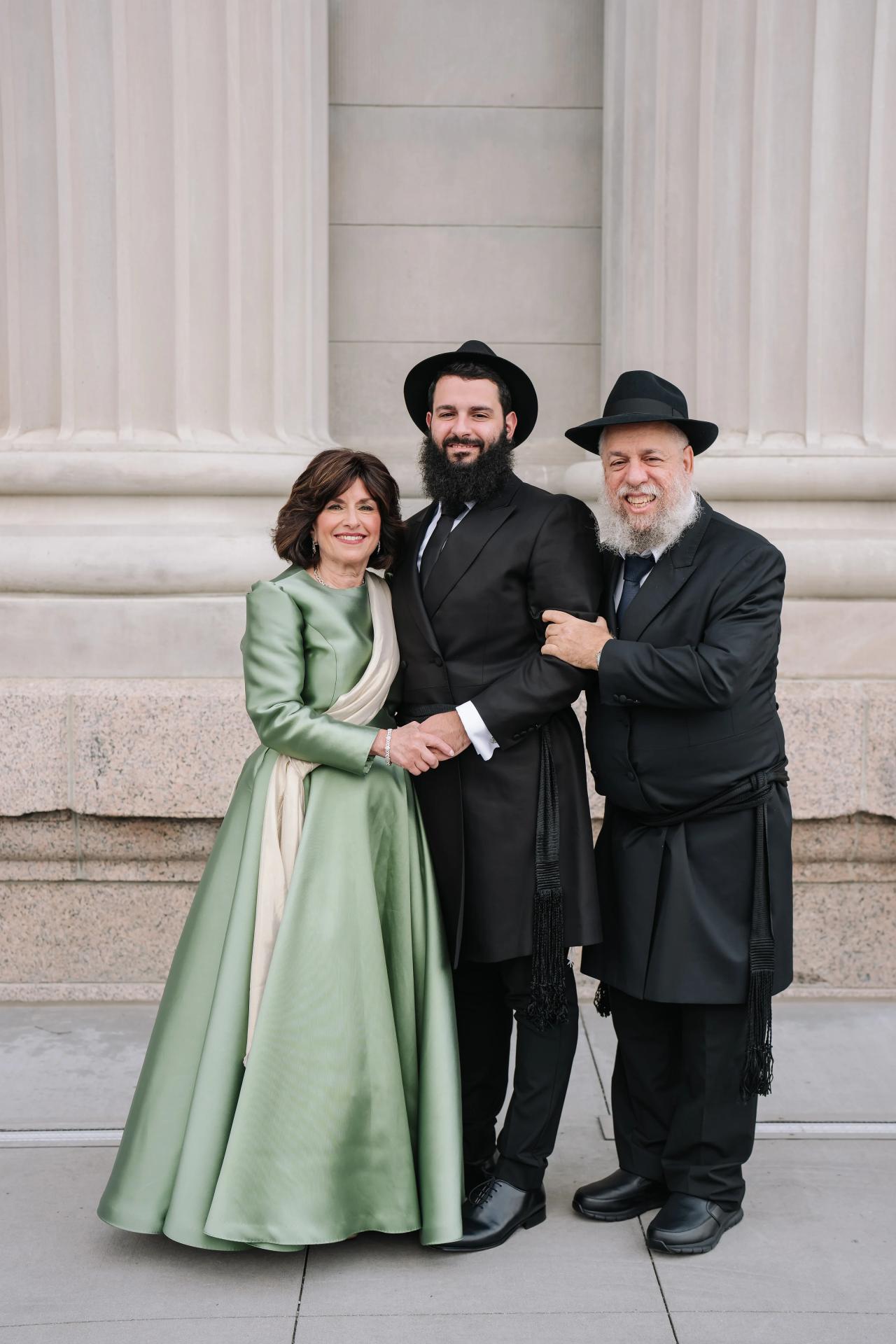 Groom with family beneath the stone columns. Jewish wedding in Detroit.