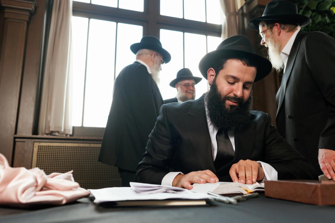 Signing the ketubah beside a sunlit window. Jewish wedding in Detroit.