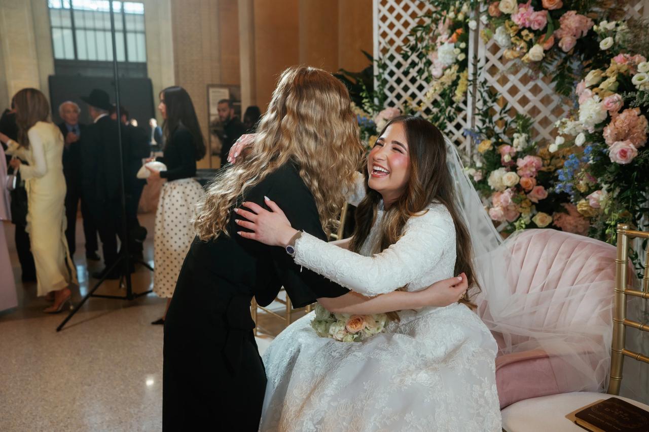 Bride sharing a joyful embrace with a wedding guest. Jewish wedding in Detroit.
