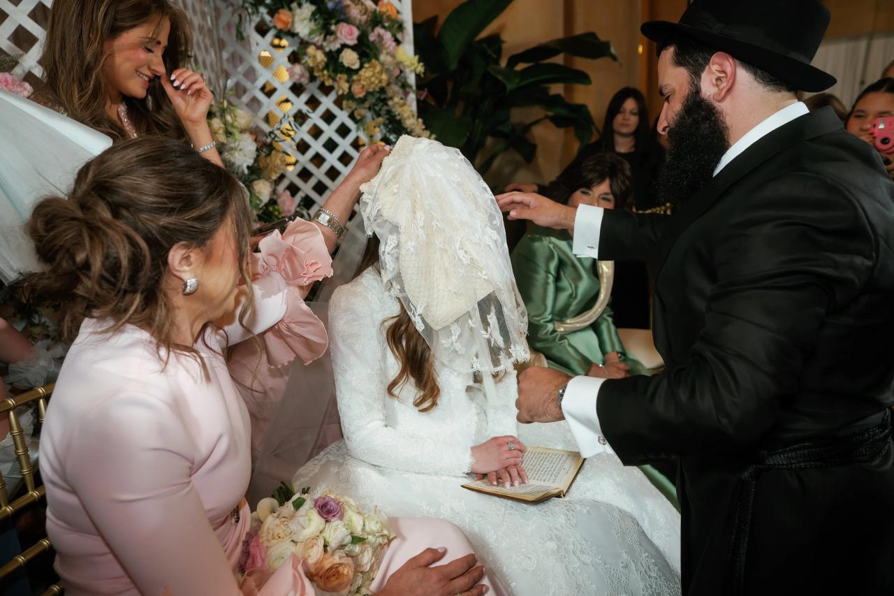 Groom lowering the bridal veil during the bedeken. Jewish wedding in Detroit.