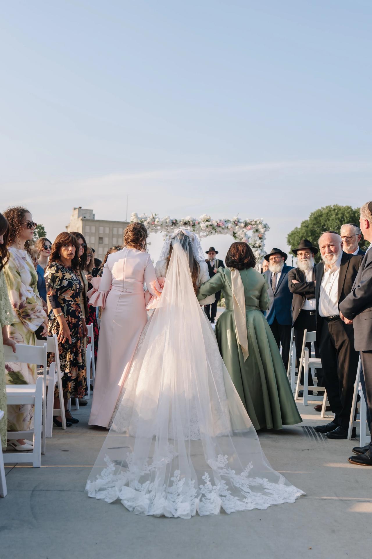 Bride walking toward the outdoor wedding ceremony. Jewish wedding in Detroit.