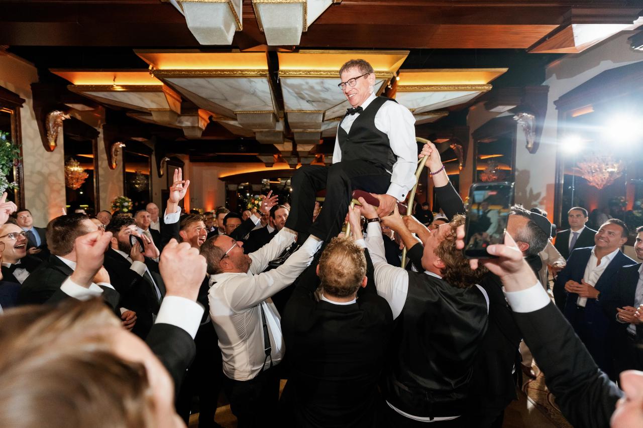 Groom lifted on a chair during the hora. Crest Hollow wedding in Woodbury, Long Island.