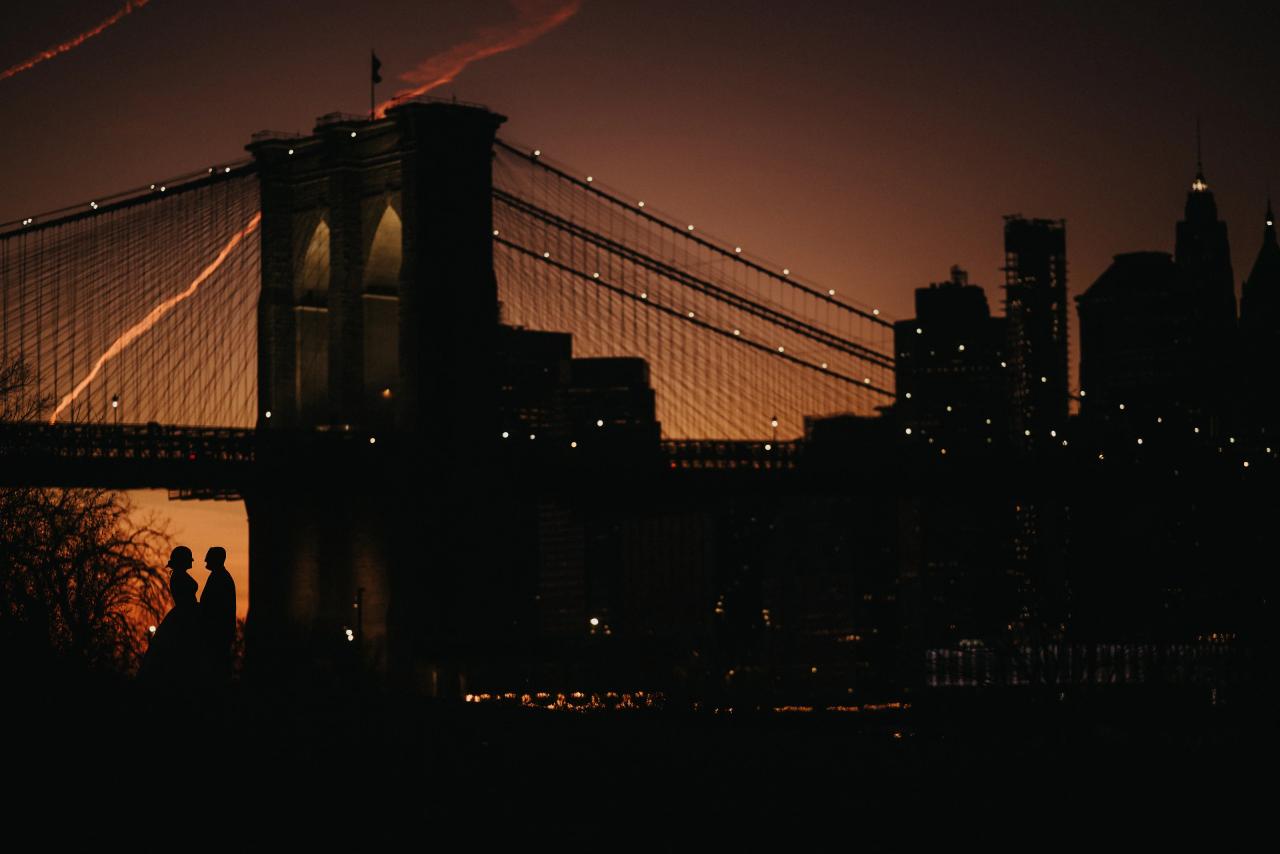 Wedding couple silhouetted against the Brooklyn Bridge after sunset