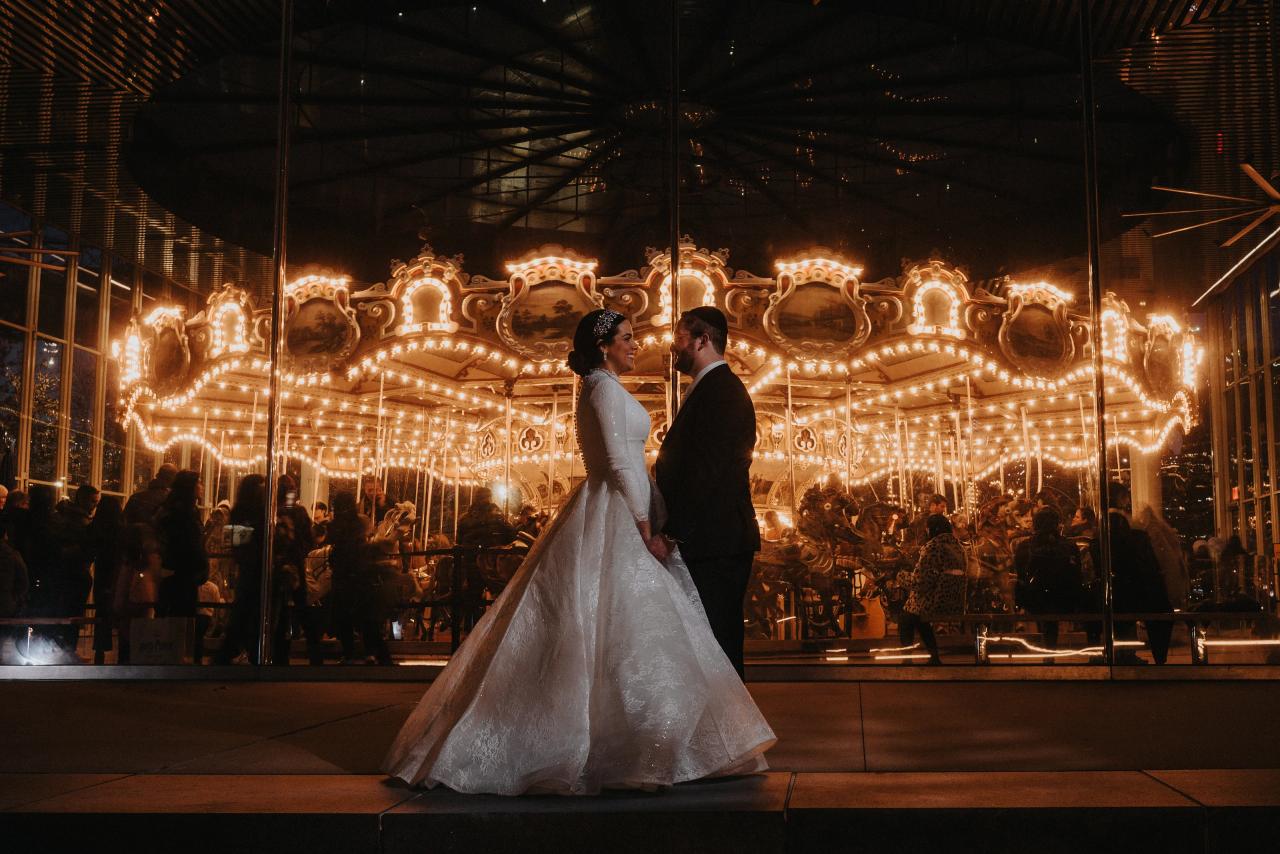 Wedding couple outside the illuminated waterfront carousel. Wedding portraits in Brooklyn, NYC.
