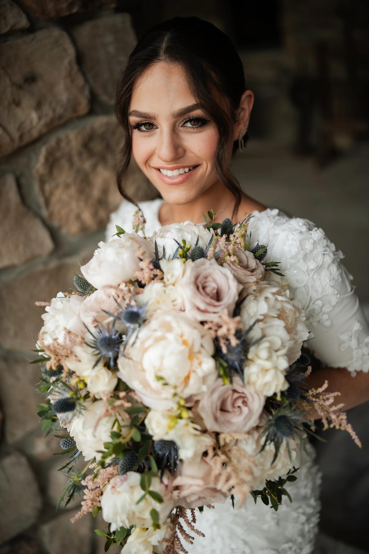 Bride smiling with her blush and ivory bouquet. Wedding at Indian Ridge.