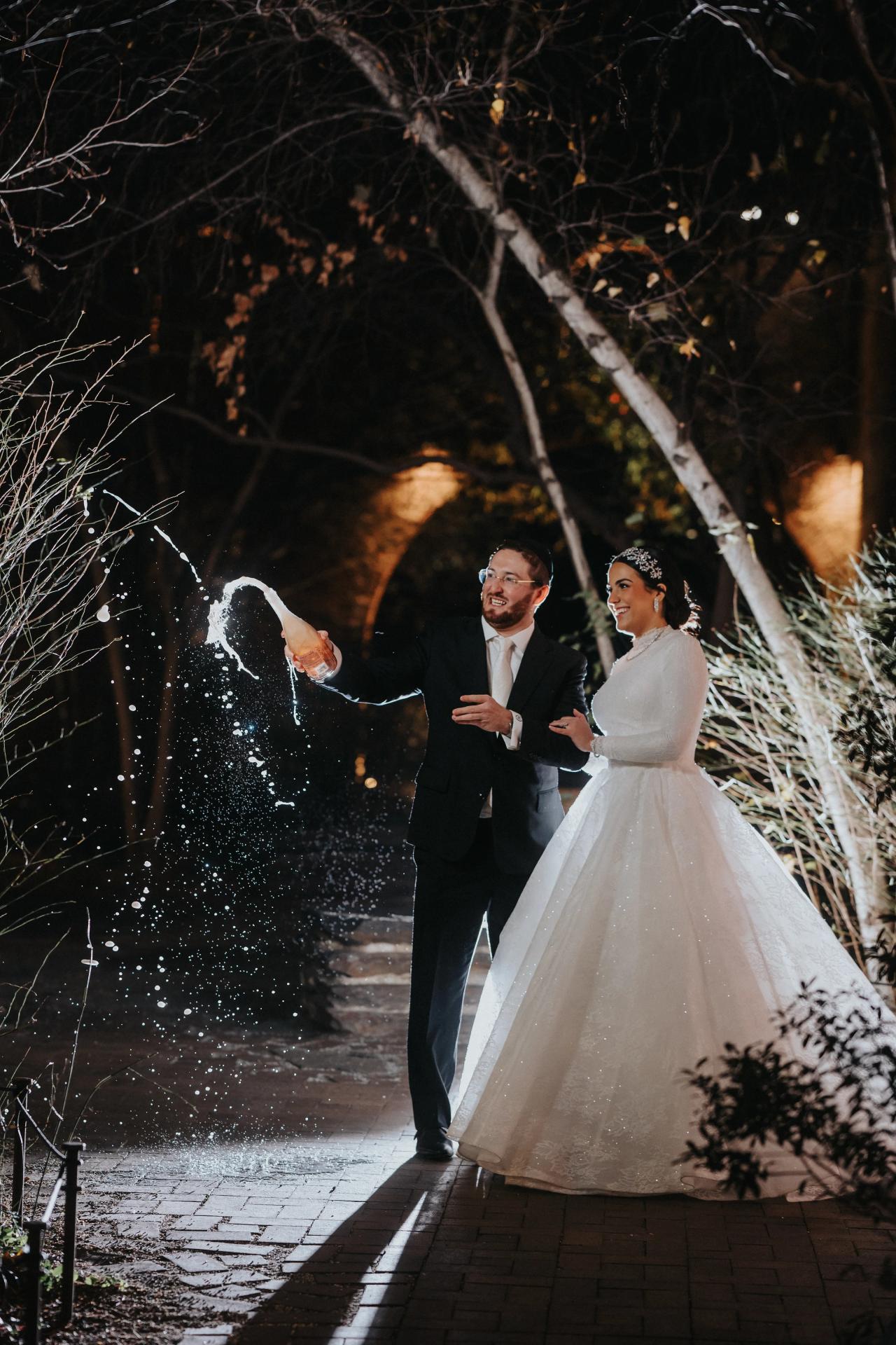 Wedding couple celebrating with a spray of sparkling wine. Wedding portraits in Brooklyn, NYC.