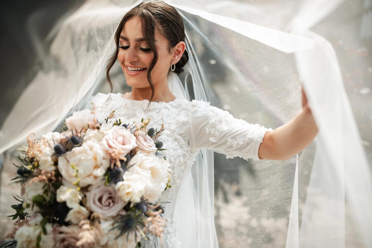 Bride holding her veil in the summer light. Wedding at Indian Ridge.