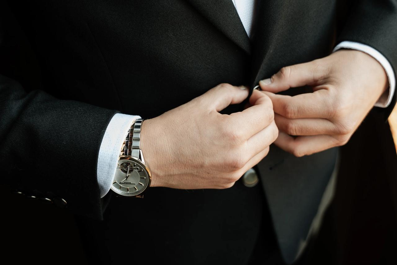 Groom adjusting his wedding suit and wristwatch. Wedding at Indian Ridge.