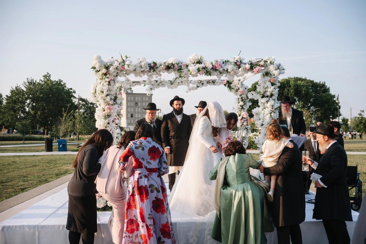 Wide view of the wedding couple beneath a flower-covered chuppah. Jewish wedding in Detroit.