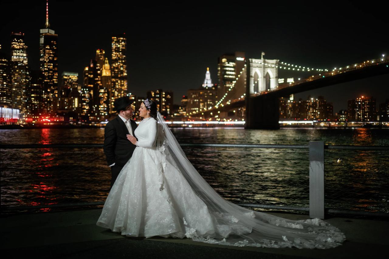 Bride and groom with the illuminated Manhattan skyline across the river. Wedding portraits in Brooklyn, NYC.