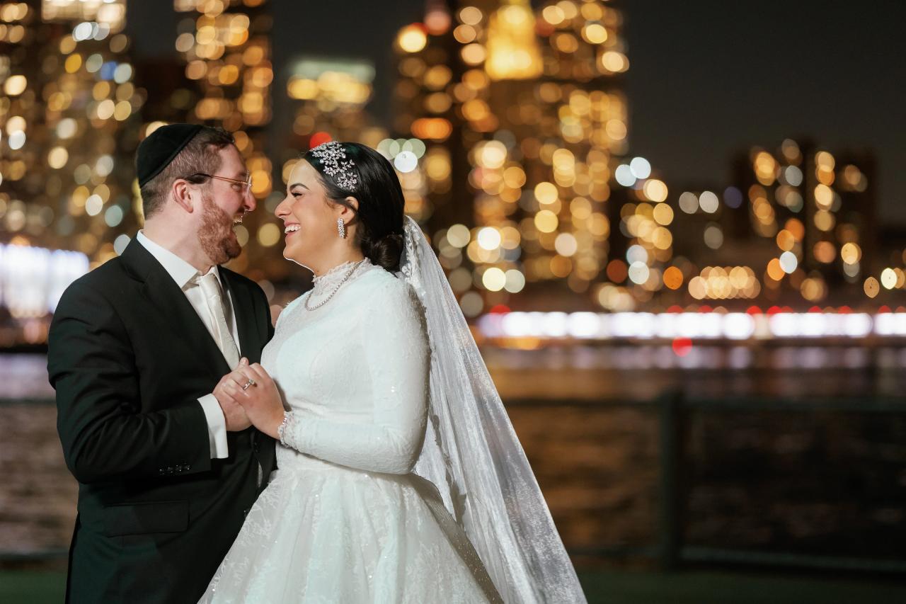 Groom kissing the bride with sparkling Manhattan lights behind them. Wedding portraits in Brooklyn, NYC.