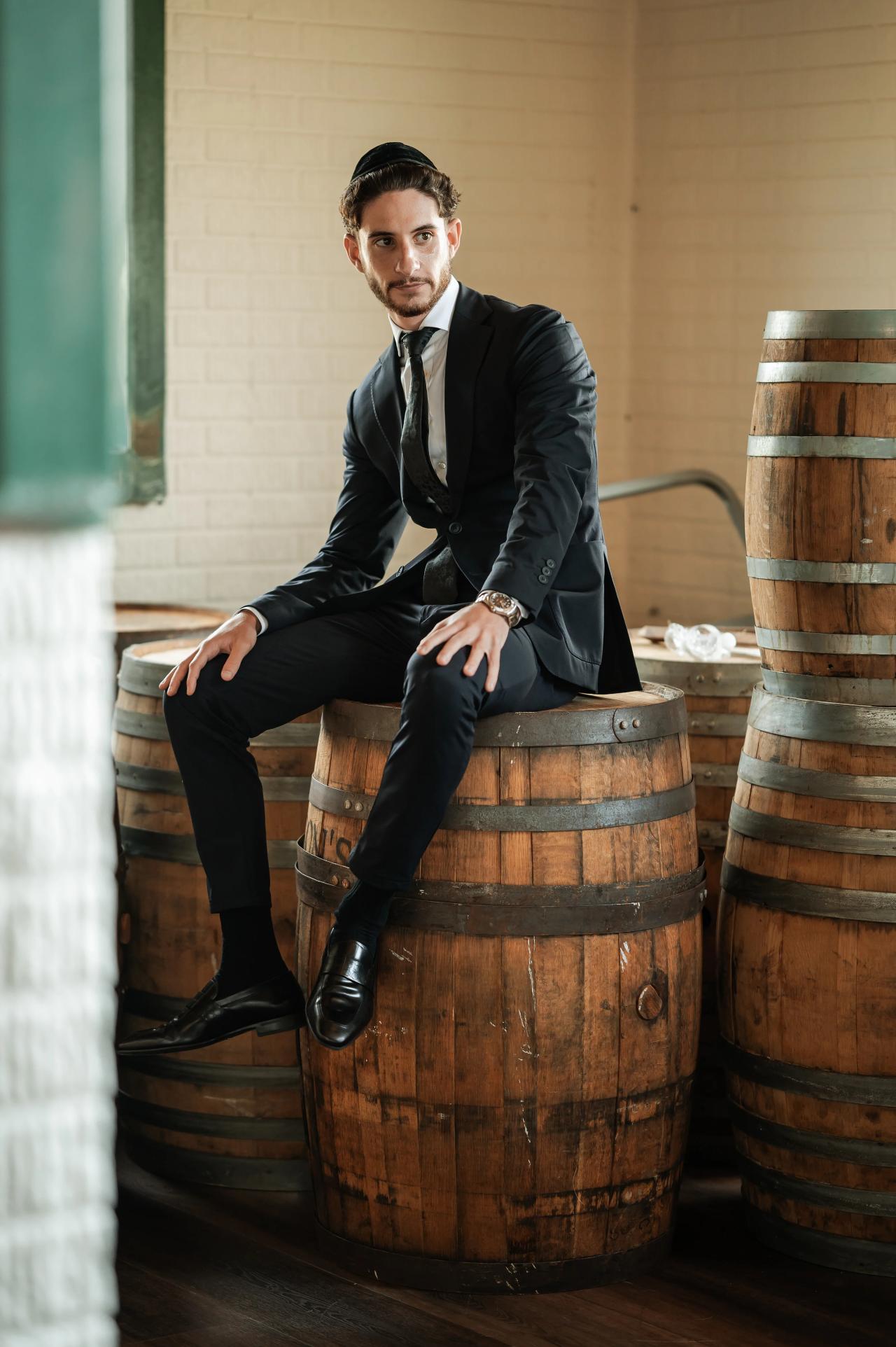 Groom seated beside a wooden barrel before the ceremony. Jewish wedding in Baltimore.