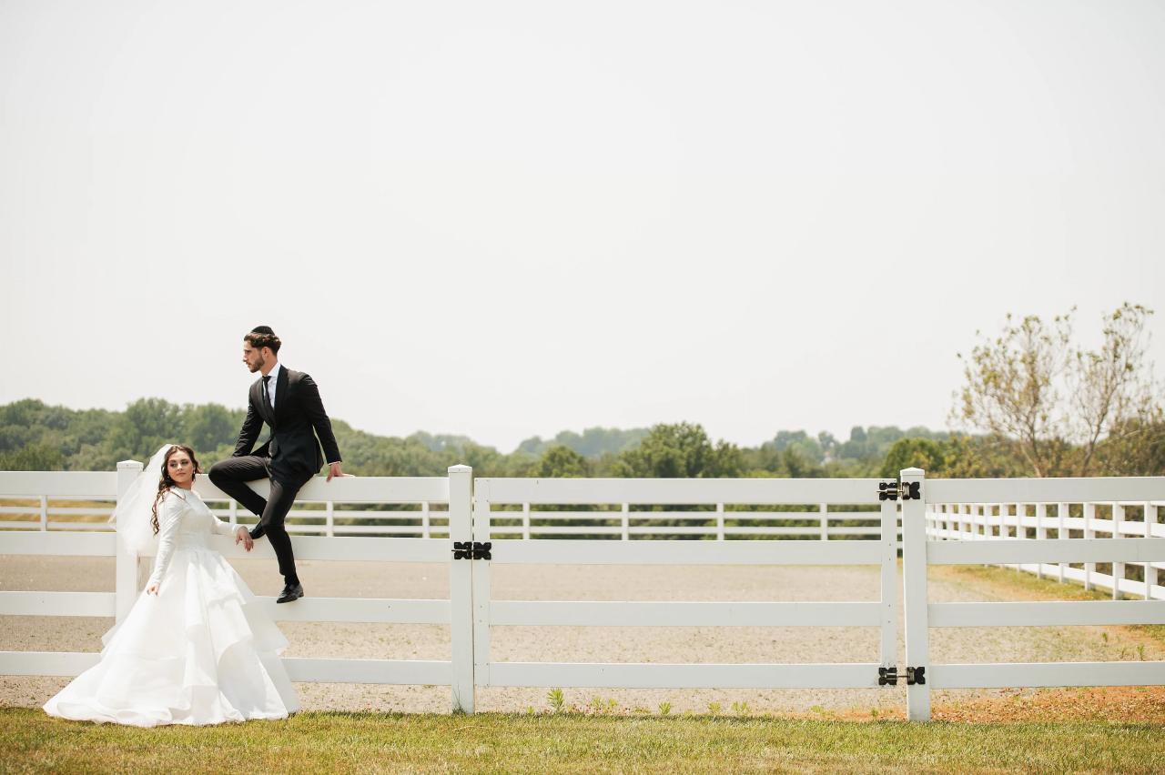 Bride and groom beside a white pasture fence. Jewish wedding in Baltimore.