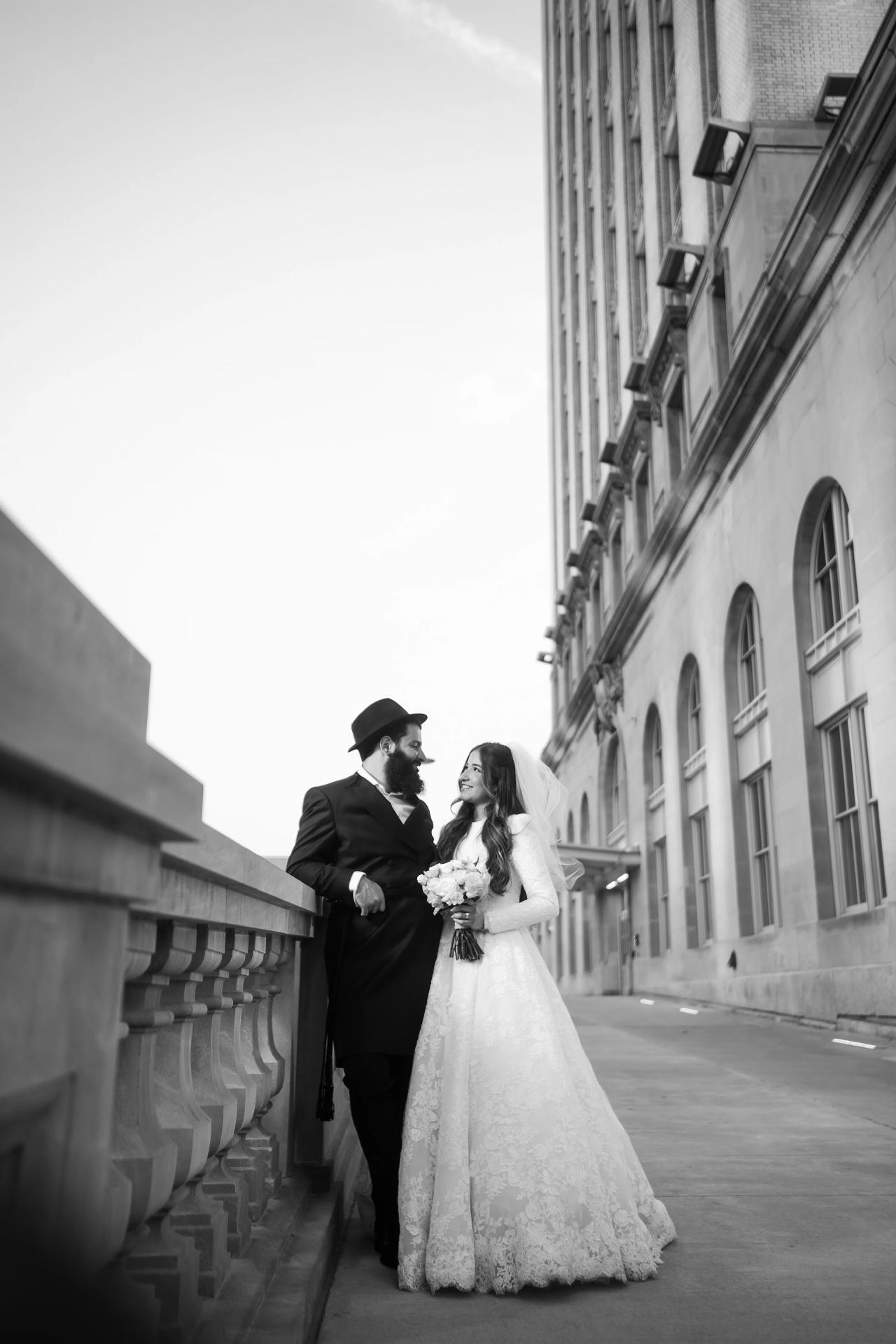 Black-and-white wedding couple portrait beneath the grand facade. Jewish wedding in Detroit.