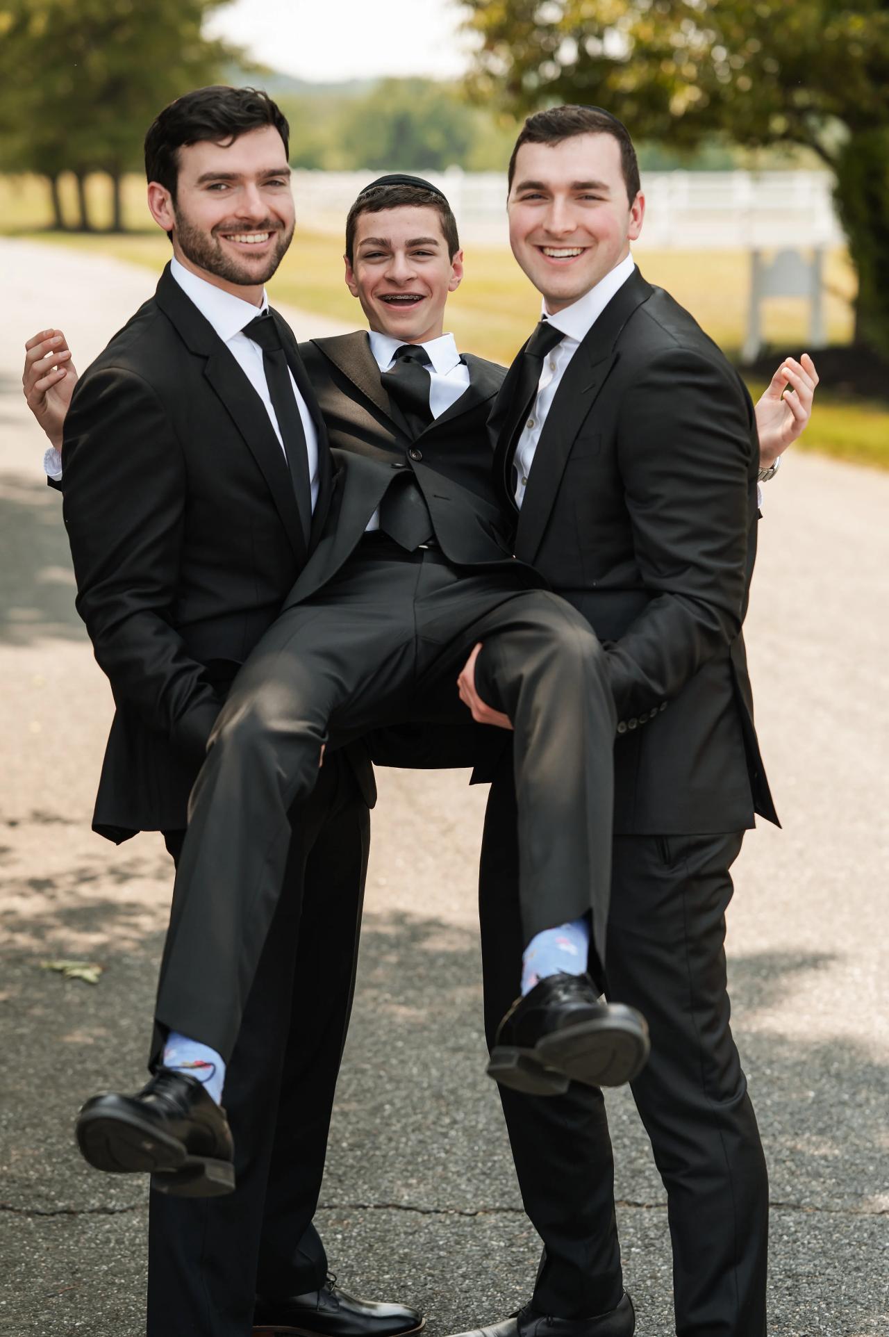 Groom lifted by friends for a playful wedding party portrait. Jewish wedding in Baltimore.