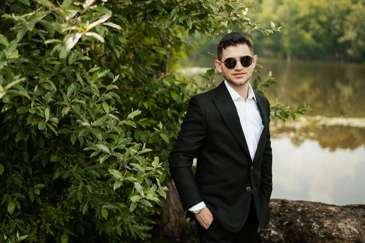 Groom in sunglasses beside the summer lake. Wedding at Indian Ridge.