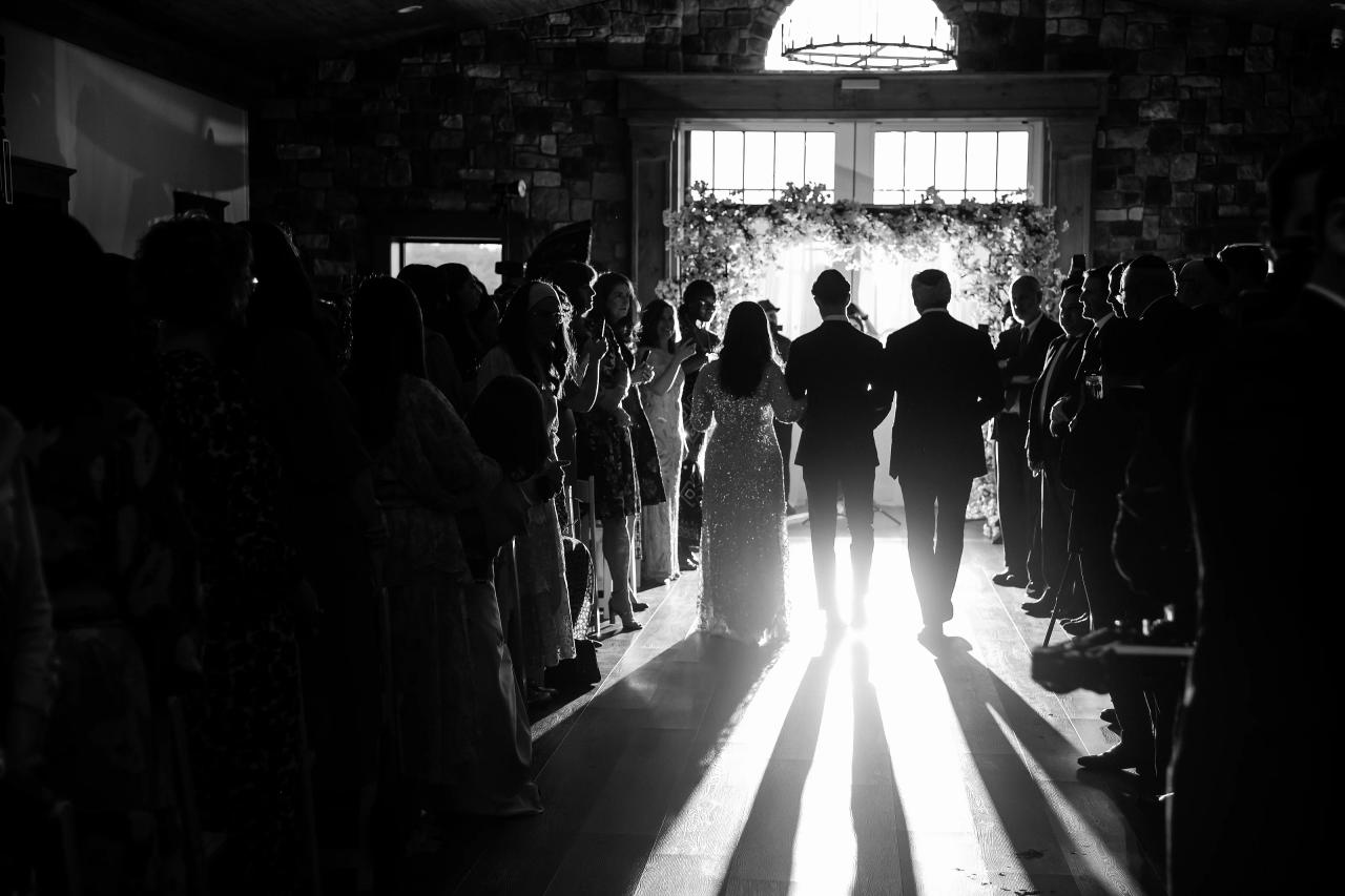 Black and white wedding processional through a sunlit doorway. Jewish wedding in Baltimore.