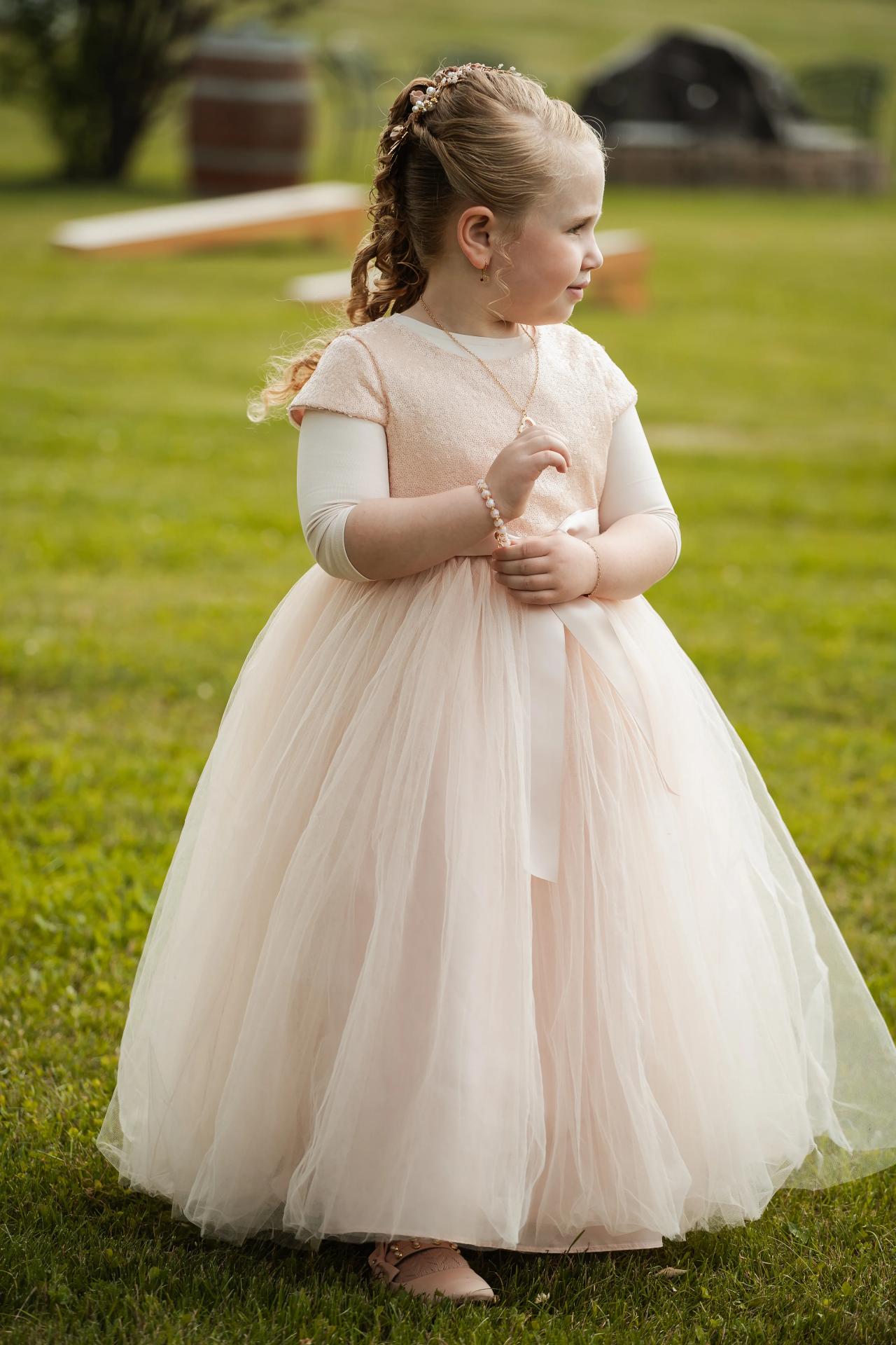 Young wedding guest in a pink dress on the lawn. Wedding at Indian Ridge.