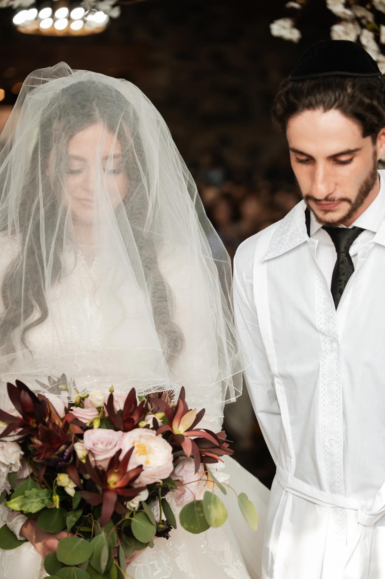 Bride and groom standing beneath the floral chuppah. Jewish wedding in Baltimore.