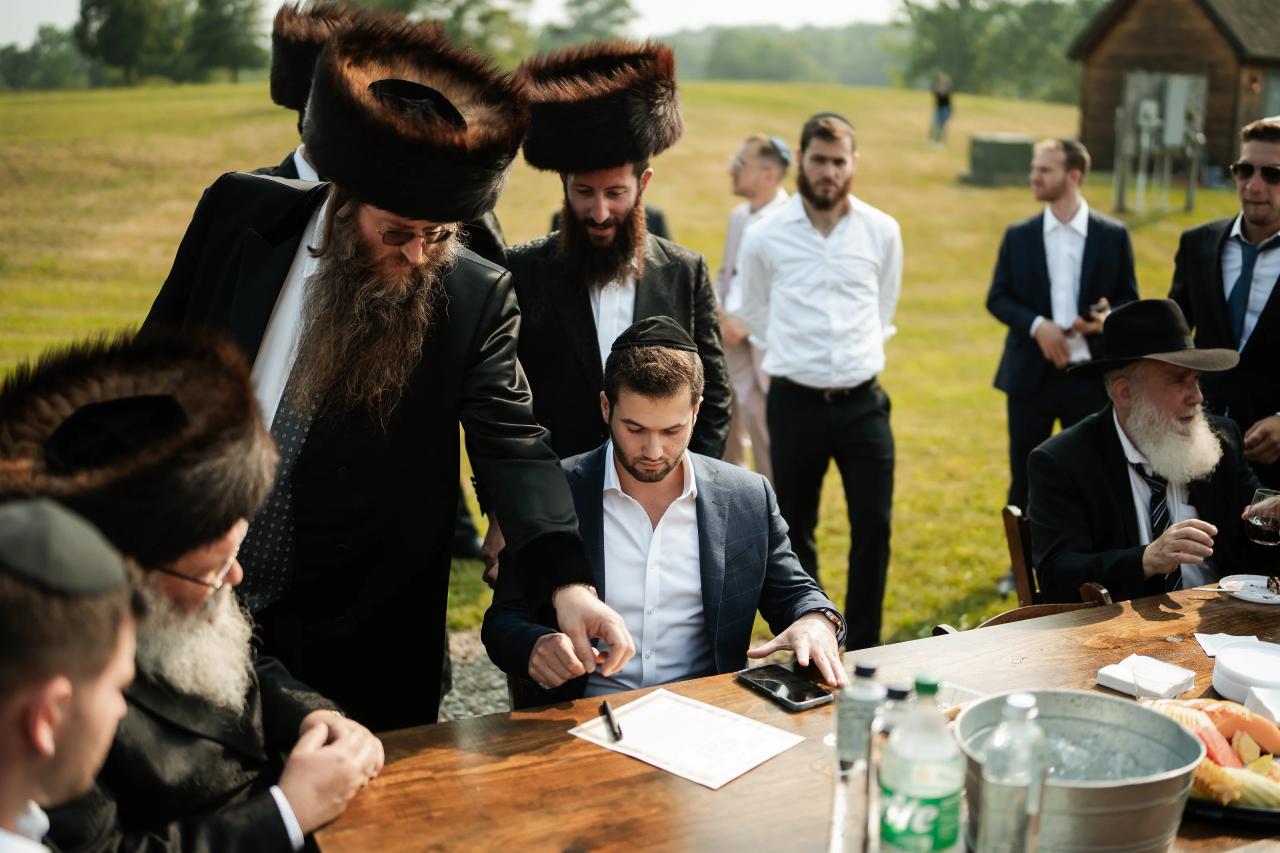 Groom and family signing the ketubah outdoors. Wedding at Indian Ridge.