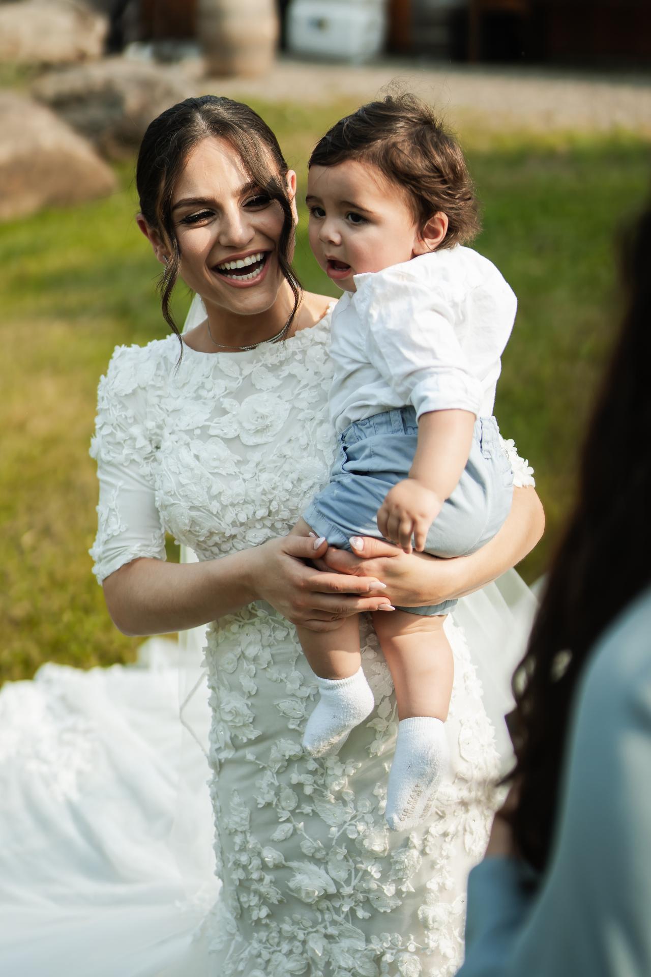 Bride holding a child before the ceremony. Wedding at Indian Ridge.