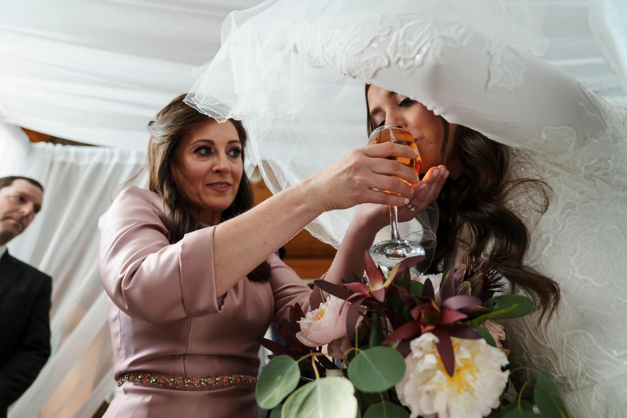 Bride drinking from the wedding wine cup beneath her veil. Jewish wedding in Baltimore.