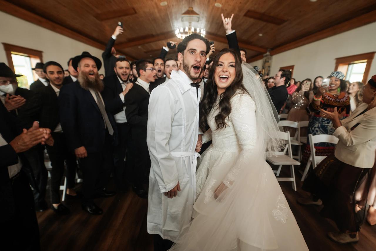 Newly married couple celebrating as guests cheer. Jewish wedding in Baltimore.
