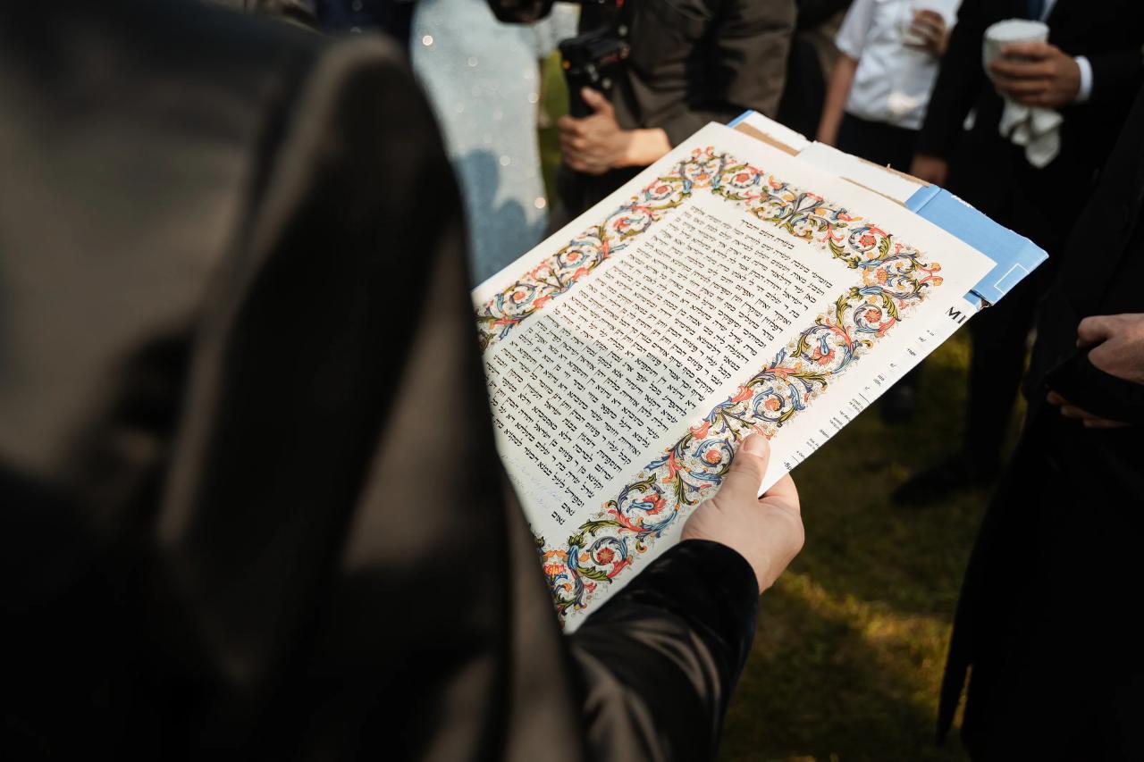 Decorated ketubah held before the lakeside ceremony. Wedding at Indian Ridge.