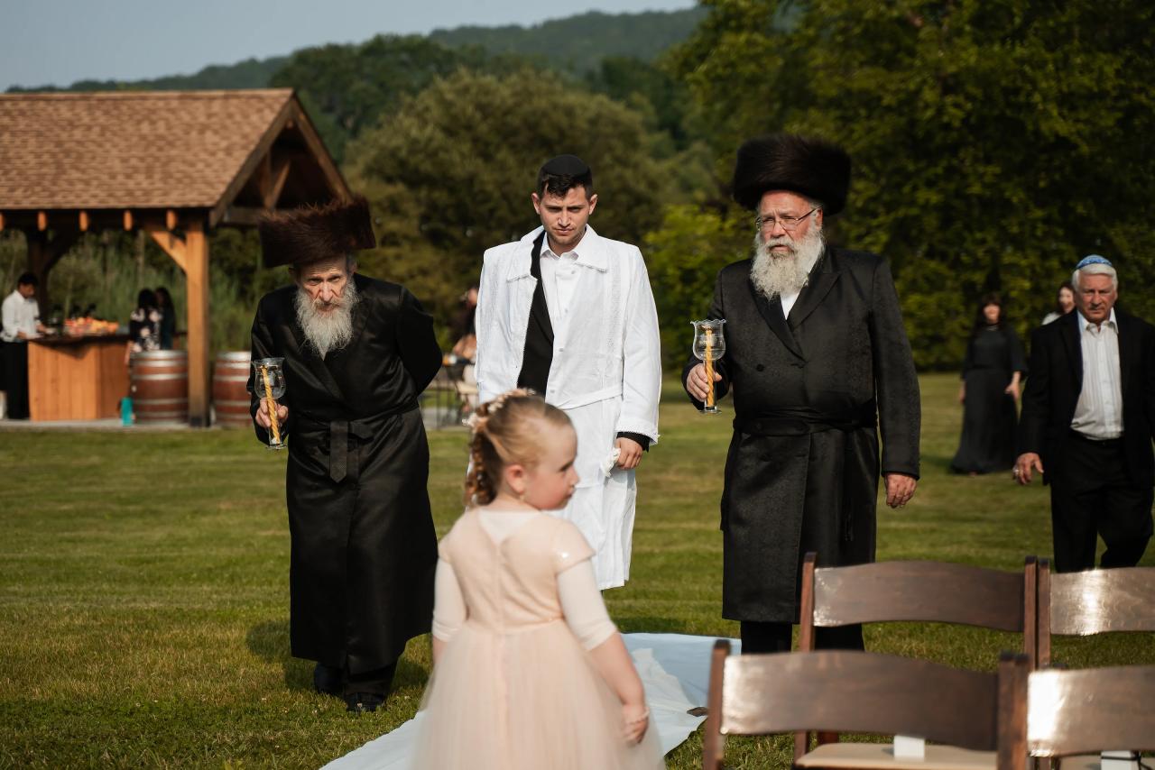 Groom walking toward the ceremony beside a flower girl. Wedding at Indian Ridge.