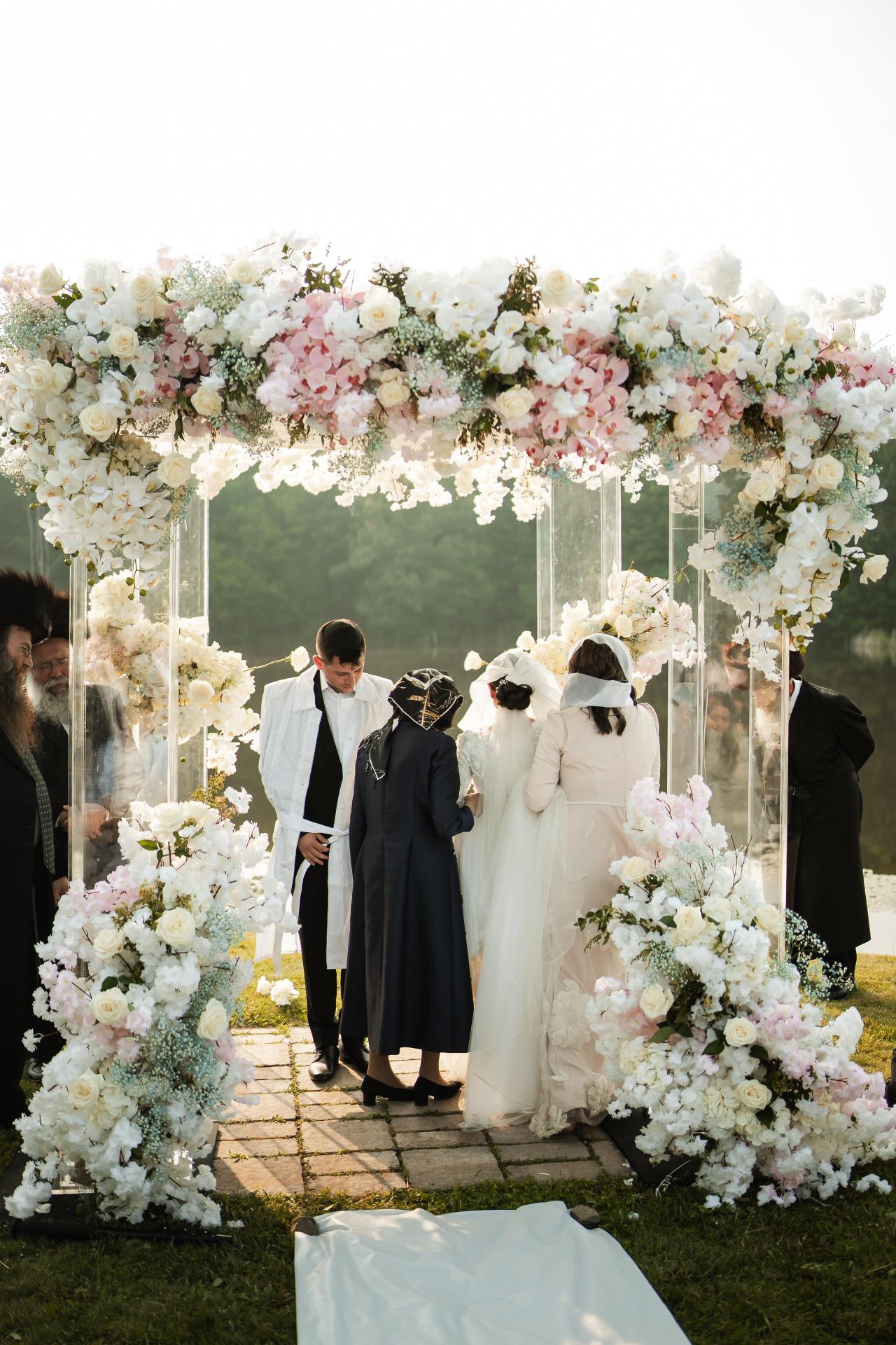 Bride and groom beneath the lakeside floral chuppah. Wedding at Indian Ridge.