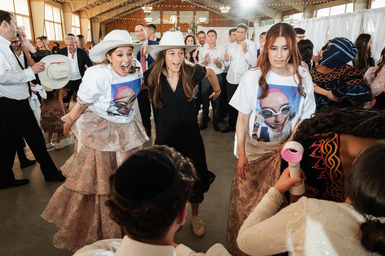Wedding guests in playful hats celebrating on the dance floor. Jewish wedding in Baltimore.
