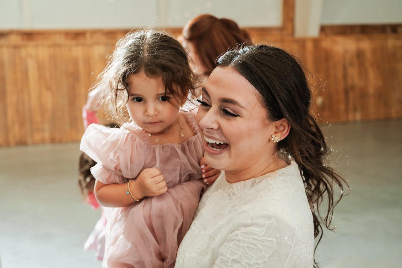 Bride holding a young flower girl at the reception. Jewish wedding in Baltimore.