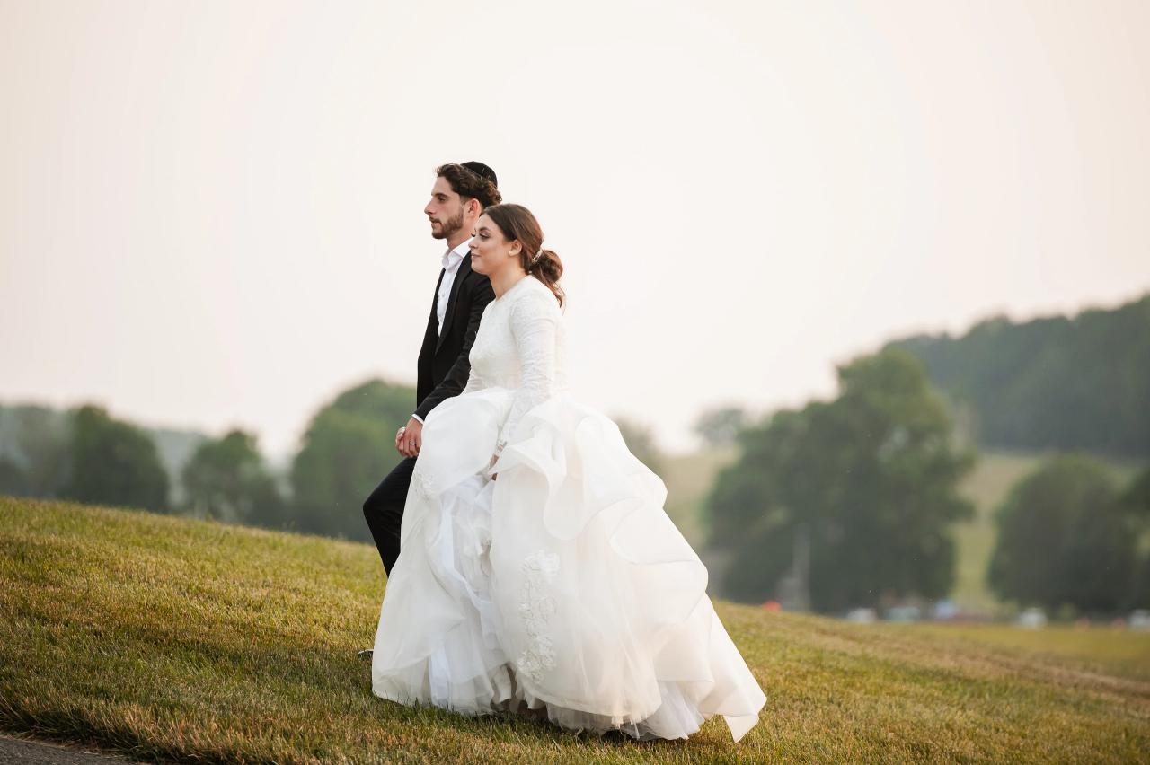 Bride and groom seated in the grass at sunset. Jewish wedding in Baltimore.