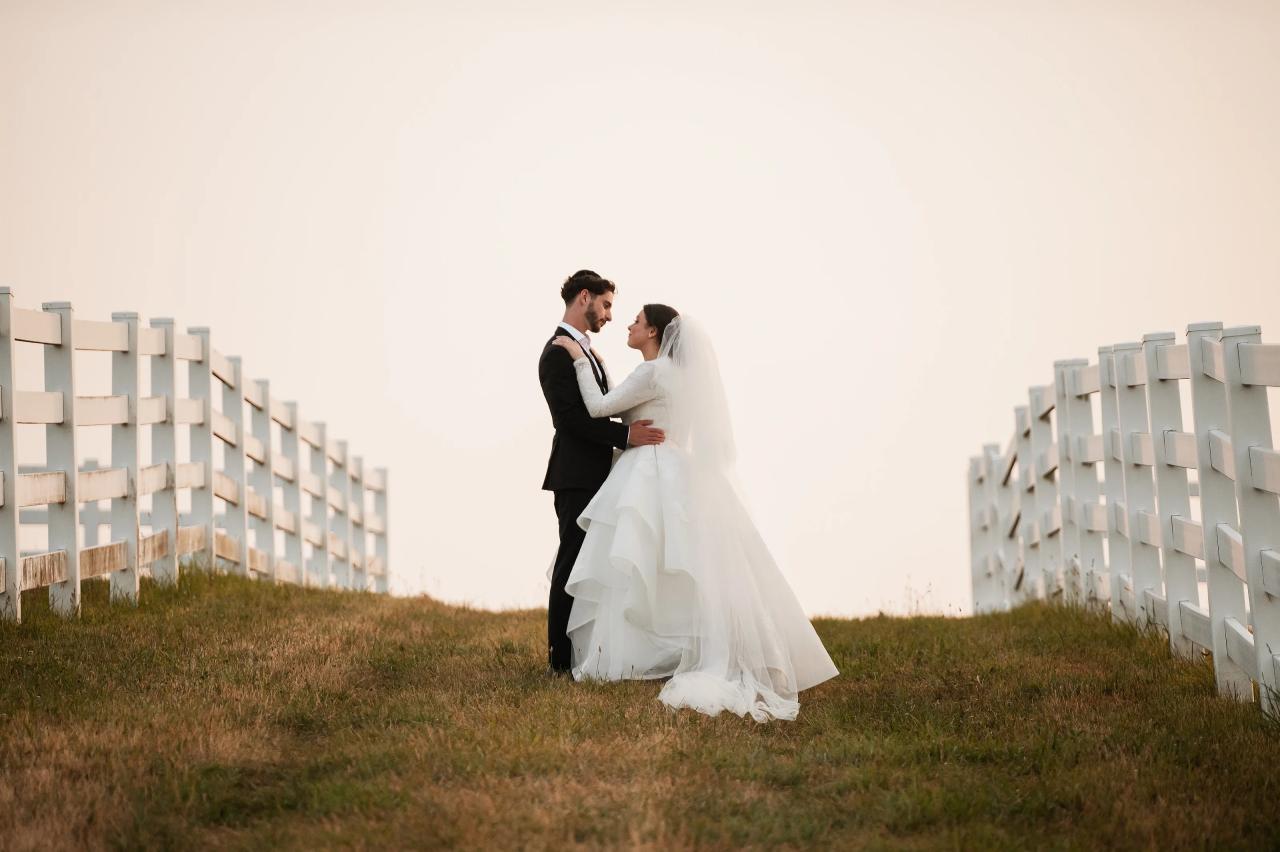 Bride and groom between white fences in evening light. Jewish wedding in Baltimore.