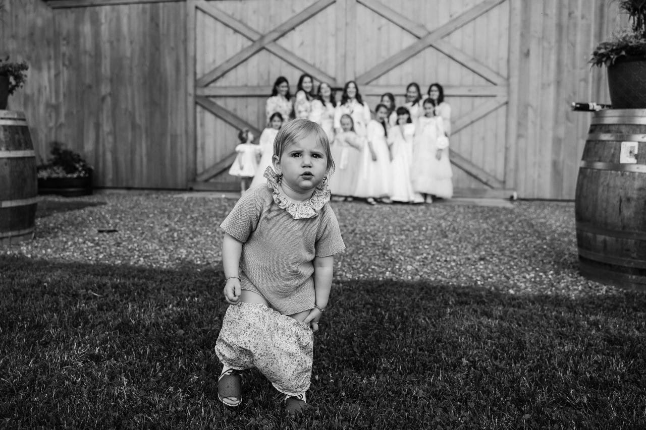 Black-and-white candid photograph of young guests outside the barn. Wedding at Indian Ridge.