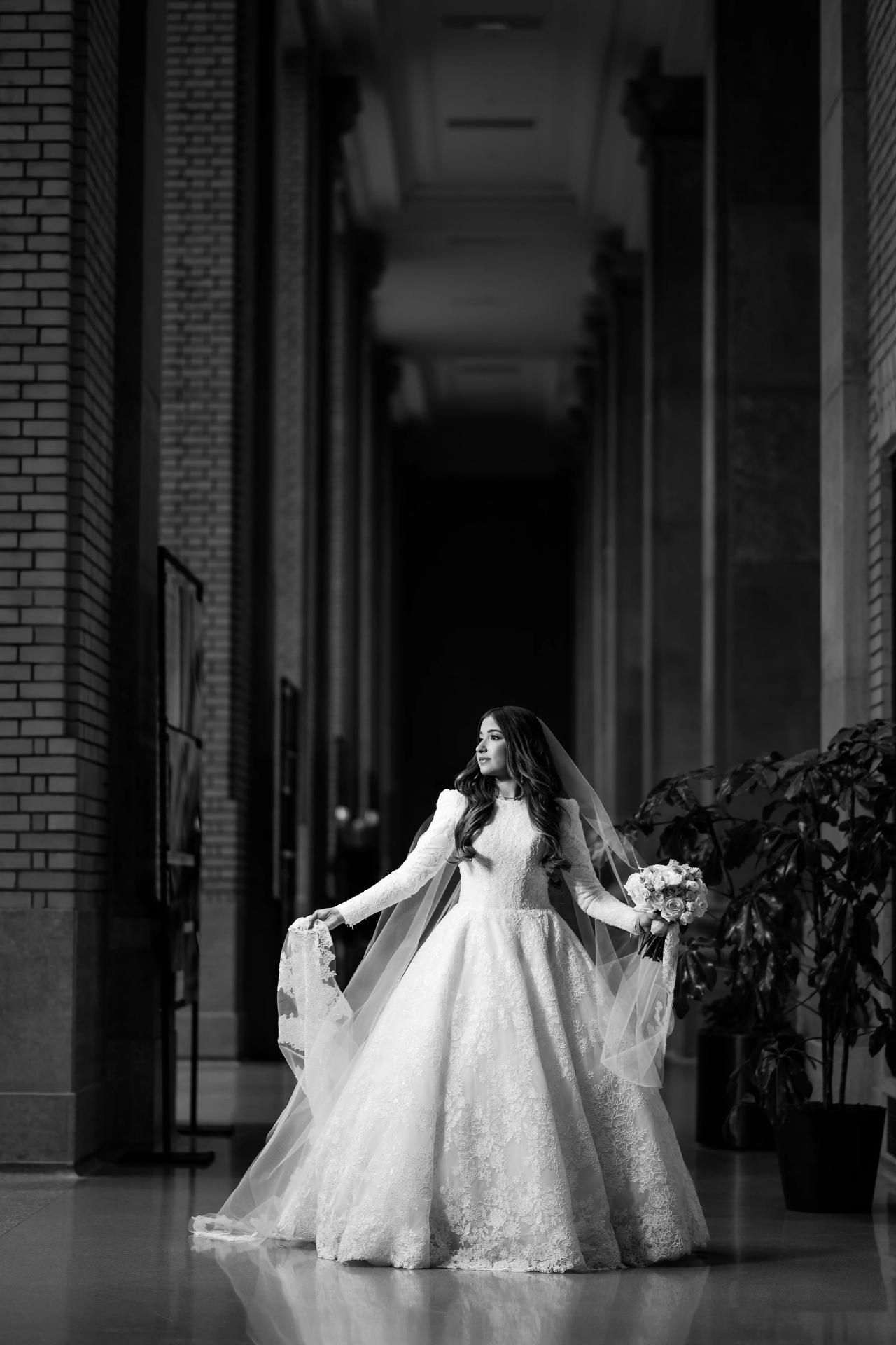 Bride holding her veil between shadowed corridor columns at a Detroit wedding