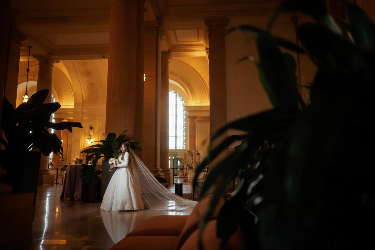 Bride and flowing veil framed by foliage in a warmly lit Detroit ballroom