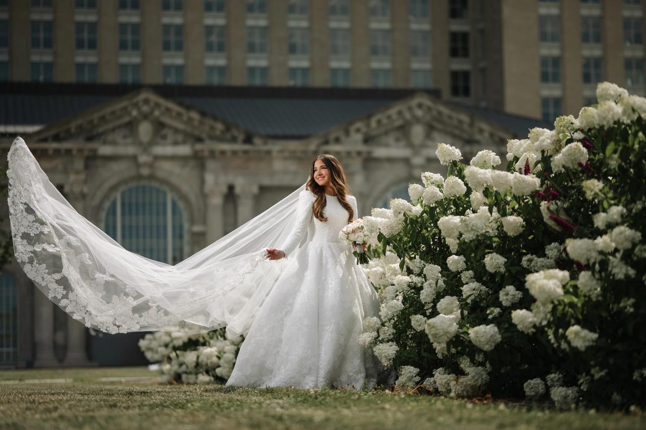 Bride spreading her embroidered veil beside white flowering shrubs in Detroit