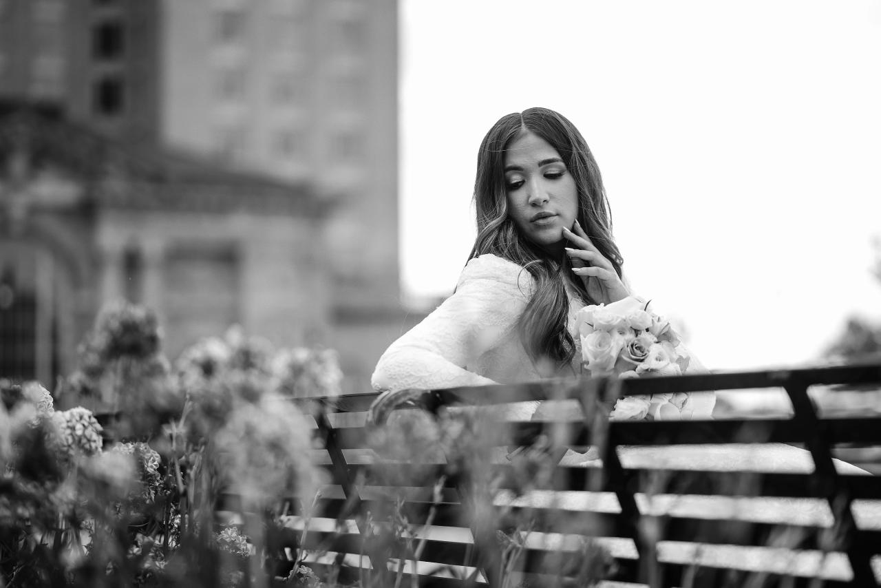 Black-and-white bridal portrait framed through garden bench rails in Detroit