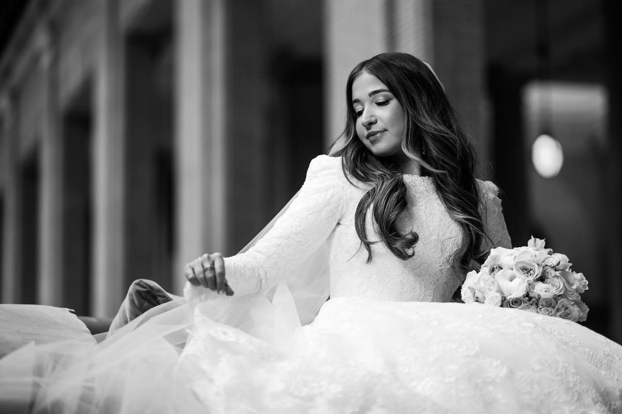 Black-and-white portrait of the bride seated with her bouquet and veil in soft window light in Detroit