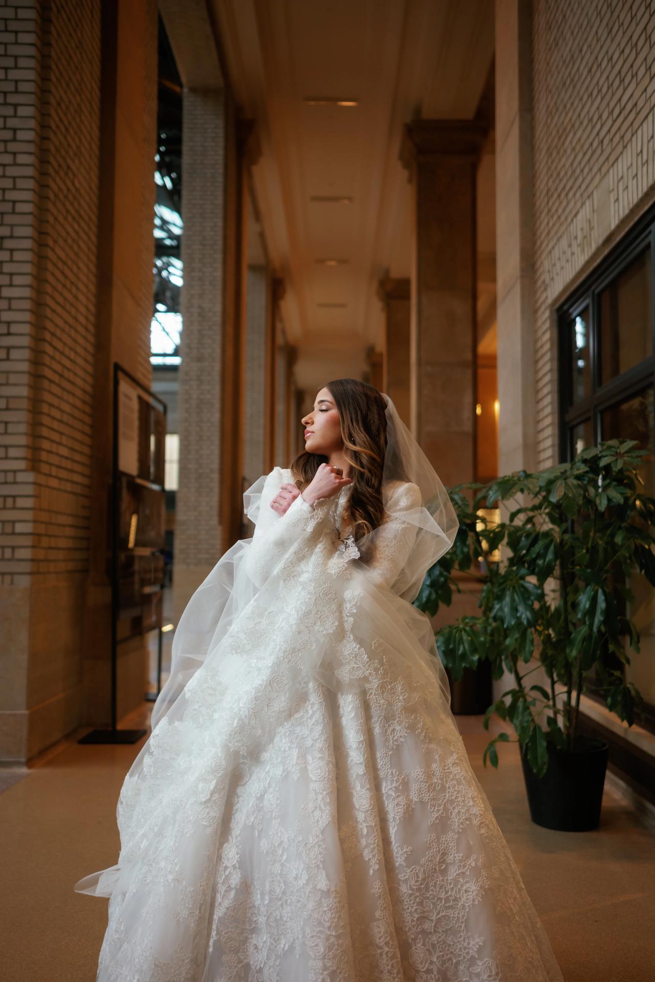 Bride framed by a warm stone corridor with her veil draped around her shoulders in Detroit