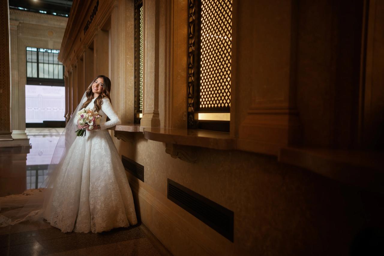 Bride leaning beside an ornate golden screen, framed by shadowed stone columns in Detroit