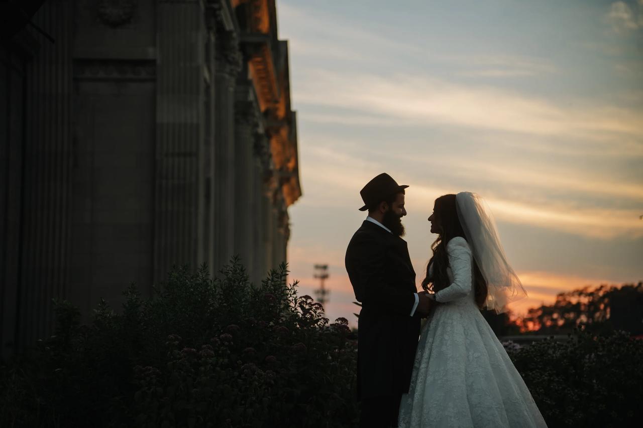Bride and groom in silhouette beside stone columns against the Detroit sunset